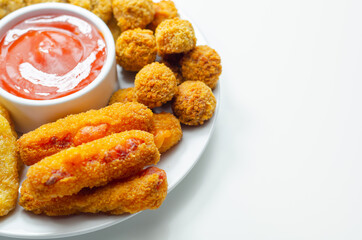Southern fried and roast chicken bites, onion rings and mozzarella stick served on the white plate with tomato sauce