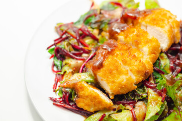 Breaded crispy chicken breast fillet with mixed salad and grated beetroot