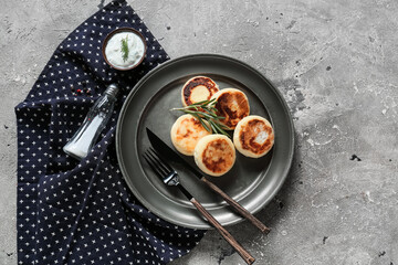 Plate with tasty cottage cheese pancakes and sauce on grey background
