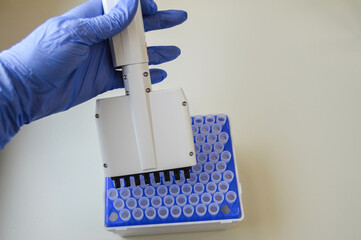 Female technician in laboratory of genetics - reprogenetics. Young technician use dispenser for...