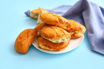 Plate of tasty sochniki with cottage cheese on blue background