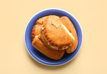 Plate of tasty sochniki with cottage cheese on beige background