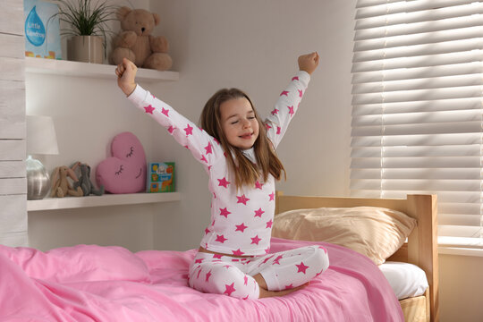 Cute little girl stretching on bed at home