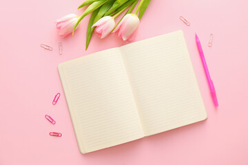 Blank notebook, pen, clips and tulips on pink background