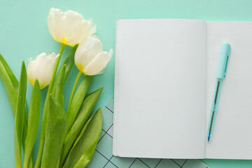 Open notebook, pen and tulips on color background, closeup