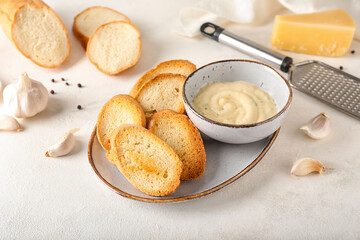 Plate of tasty croutons and bowl with sauce on white background