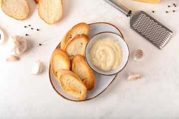 Plate of tasty croutons and bowl with sauce on white background