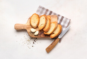 Wooden board with tasty croutons on white background