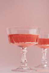 Two crystal glasses of rose sparkling wine or champagne on pastel pink background. Summer drink concept. Minimal creative composition with copy space.
