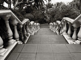 Black and white tile stairs with 16th century style bannisters that lead to lush, tropical garden.