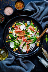 Tasty salad - prosciutto crudo, parmesan and fresh, green vegetables on wooden table
