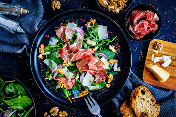 Tasty salad - prosciutto crudo, parmesan and fresh, green vegetables on wooden table
