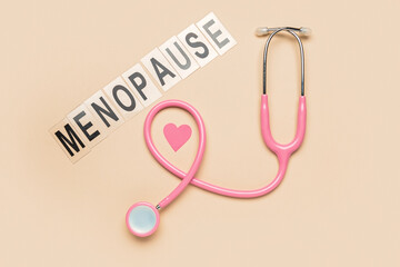 Fototapeta premium Word MENOPAUSE with stethoscope and paper heart on beige background