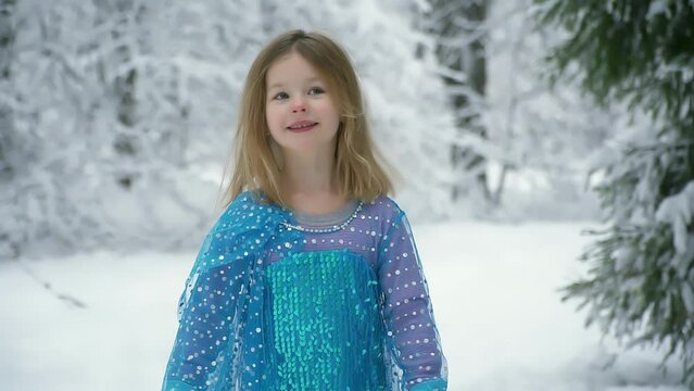 beautiful little girl in masquerade blue dress walks in snowy frosty park. smart girl in suit rejoices in Christmas and new year. Man enjoys beauty and nature. Have fun, laugh and run. happy childhood