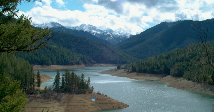 Tilt down from clouds to beautiful shot of Applegate Lake Oregon with snowy Mount Ashland visible in background