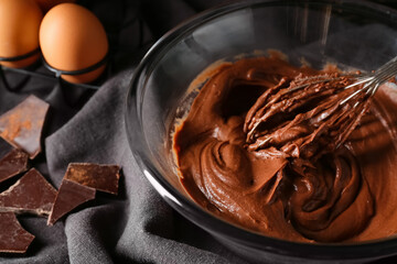 Bowl with fresh dough for preparing chocolate brownie on table, closeup