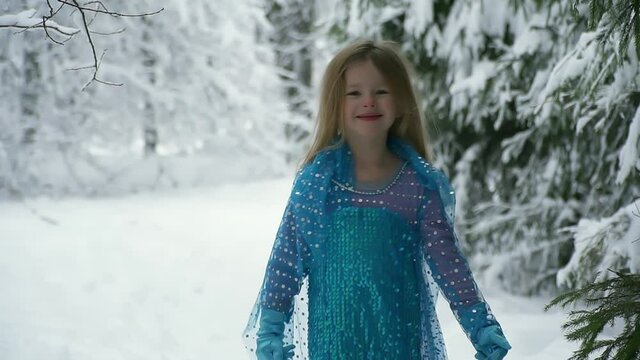 beautiful little girl in masquerade blue dress walks in snowy frosty park. smart girl in suit rejoices in Christmas and new year. Man enjoys beauty and nature. Have fun, laugh and run. happy childhood
