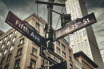 Fifth Ave 5th Ave, New York City sign, view from low angle with building facade and sky in...