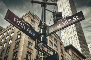 Fifth Ave 5th Ave, New York City sign, view from low angle with building facade and sky in thebackground, america, usa