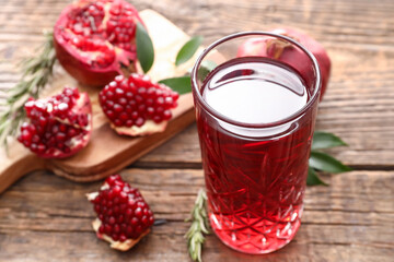 Glass of delicious pomegranate juice on wooden background