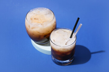 Glasses of White Russian cocktail on blue background