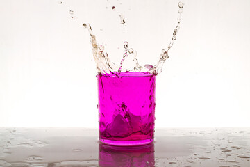 salpicadura de agua con cubitos de hielo en vaso de vidrio