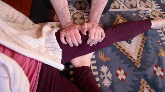 A short movie shot up close with room for copy. Camera pans out from the hands of a male masseur kneading the quadriceps and thigh of female client.