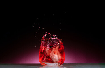 salpicadura de agua con cubitos de hielo en vaso de vidrio