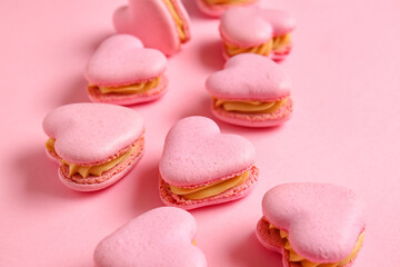 Obraz na płótnie Canvas Tasty heart-shaped macaroons on pink background, closeup
