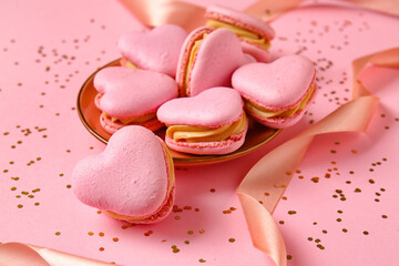 Plate with tasty heart-shaped macaroons and confetti on pink background, closeup