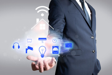 Man in jacket holding a house connected by wifi to different electronic devices. Home automation in the home