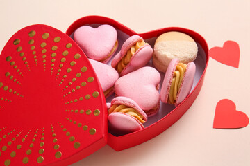 Box with tasty heart-shaped macaroons on beige background