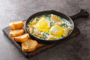 New Orleans Style Eggs Sardou Poached Eggs With Artichoke, Spinach and Hollandaise close up in the plate on the table. Horizontal