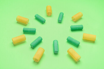 Different hair curlers on green background