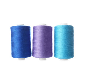 Blue and lilac sewing thread spools on white background