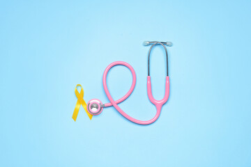 Golden awareness ribbon and stethoscope on blue background. International Childhood Cancer Day