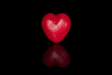 a red heart painted with a brush with a reflection on a black background