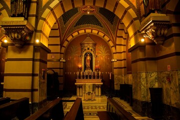 Altar no interior de mosteiro com imagens de santos, arte clássica e velas acesas. 