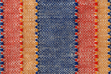 Macro texture of plain weave fabric. Striped cloth background of red, blue, orange and white...