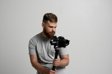 Professional bearded videographer holding camera which set on 3-axis gimbal. Videographer using steadicam. Pro equipment helps to make high quality video without shaking.