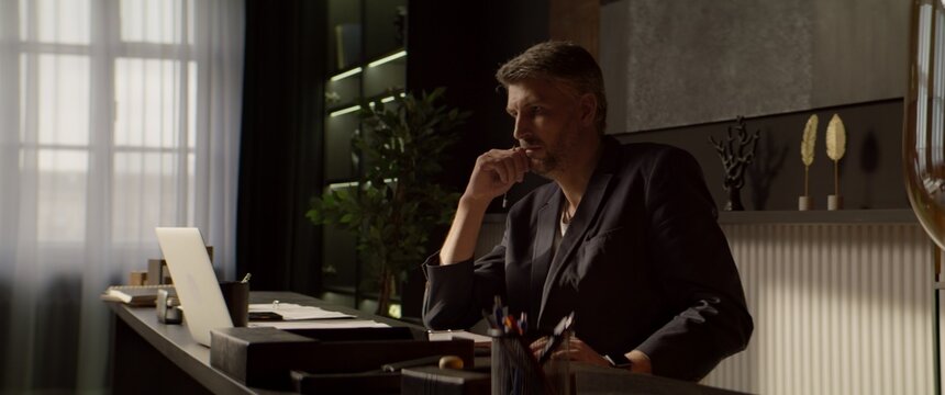 CU Portrait of 40s Thoughtful Caucasian businessman working on a laptop in the office. Shot with 2x anamorphic lens