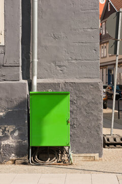 Ein grüner Stromverteiler vor einer grauen Hausfassade