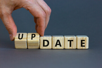 Date or update symbol. Businessman turns wooden cubes and changes the concept word date to update. Beautiful grey table, grey background, copy space. Business and date or update concept.