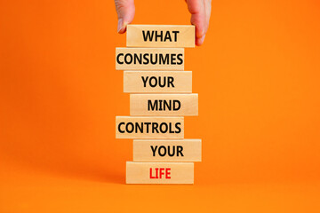 Motivational symbol. Wooden blocks with words What consumes your mind controls your life. Beautiful orange background, copy space. Businessman hand. Business, motivational lifestyle concept.