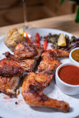 Georgian cuisine dish roasted chicken tapaka with sauce on plate in restaurant