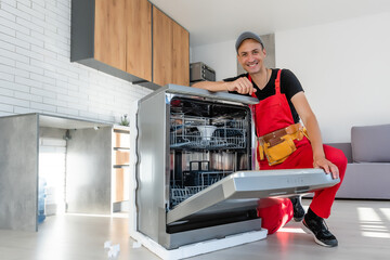 Young Repairman Service Worker Repairing Dishwasher Appliance In Kitchen