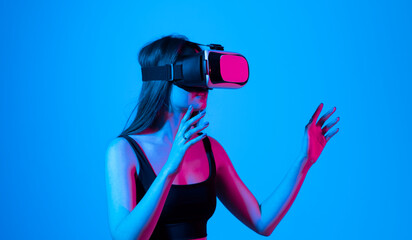 Virtual reality, technology, entertainment and people. Portrait of teen woman in vr glasses playing in online game with 3D simulation, in neon light.