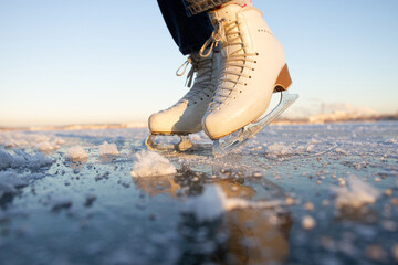 close-up of women's skates on a frosty winter day on a frozen lake in the park. ice skating at dawn