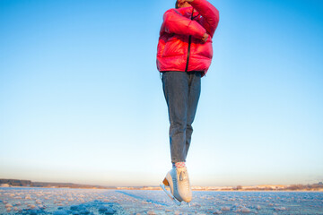 a sporty girl shows an element from figure skating on the lake. there is a large expanse and a lot of sky in the background