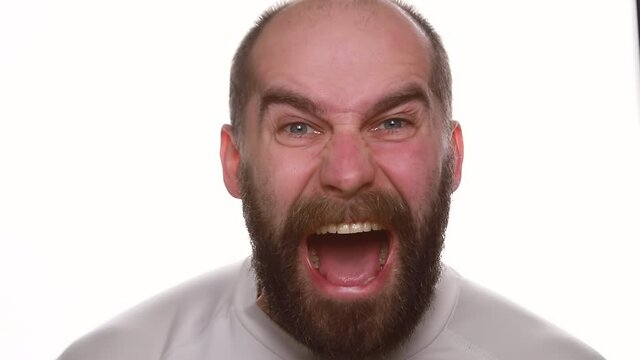 Portrait of angry man screaming in studio. Rage guy shouting on white background. Male person with aggressive face expression. Closeup angry model yelling at camera in slow motion